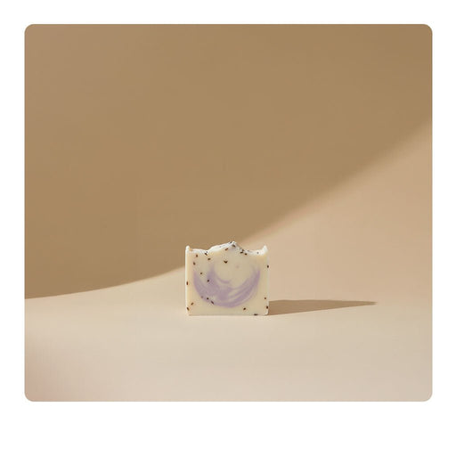 A shelf displays various handmade soaps labeled with names like Sweetgrass, Passionflower, and Sunflower. The background shows wooden shelves with more soaps and items in a cozy store setting.