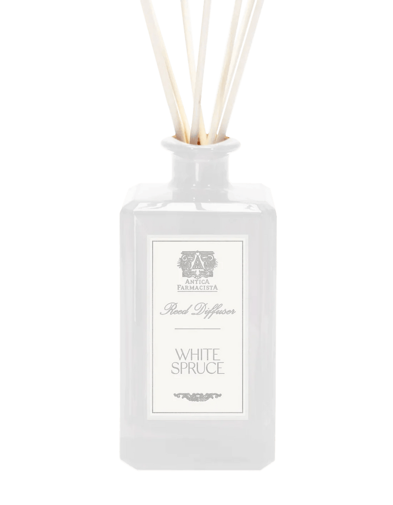 A 320ml clear glass bottle from Antica Farmacista, the White Spruce Reed Diffuser, features evergreen fragrance sticks with an apothecary-inspired label that boasts an elegant design and classic font, exuding timeless charm.