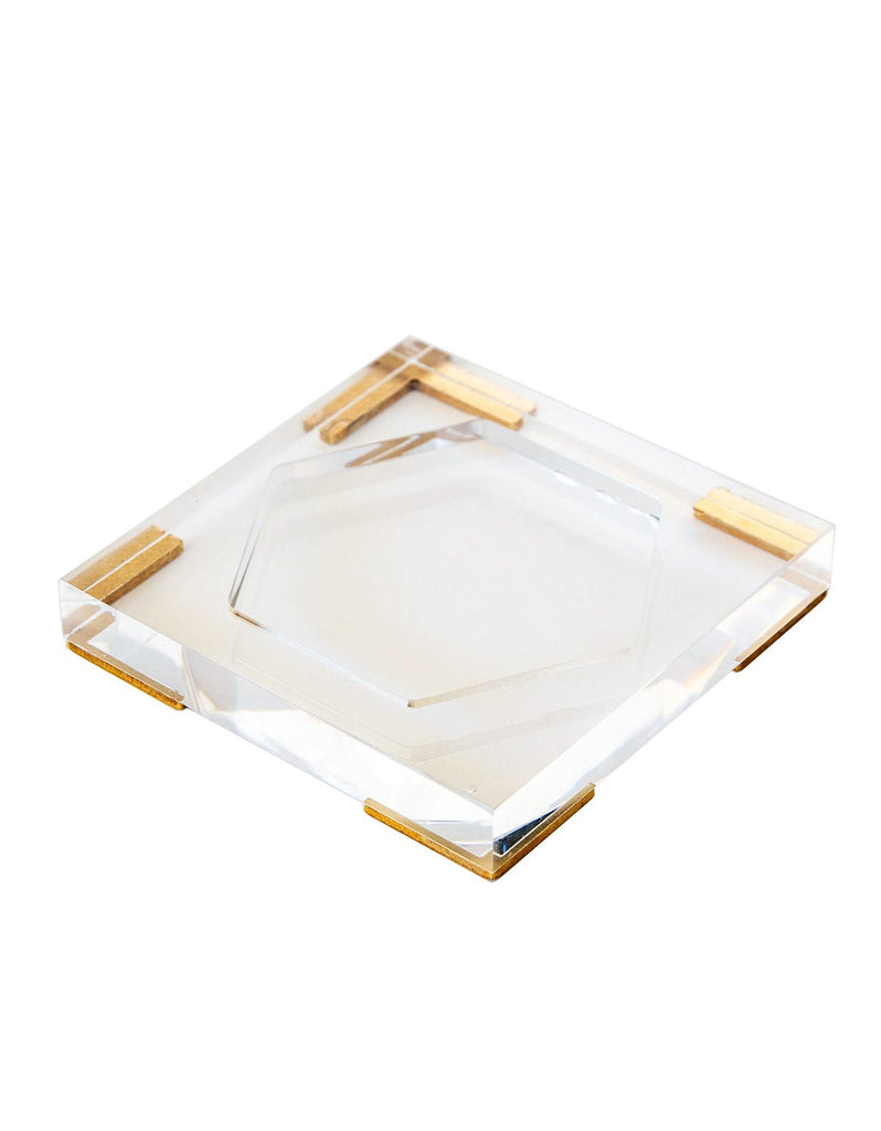 The Antica Farmacista - Acrylic Tray for 9oz Candle, a sleek hexagonal piece with gold-accented corners, sits on a white background. Its clear surface beautifully complements any 9oz candle, offering a blend of elegance and functionality.