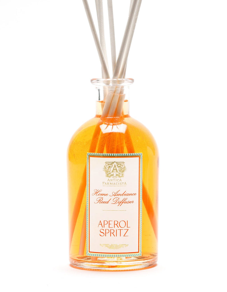 The Antica Farmacista Aperol Spritz 250ml Reed Diffuser features a clear bottle with vibrant orange liquid, accented by reed sticks that diffuse a Citrus Spectrum fragrance. The label displays an elegant logo and text, elevating the sophistication of this diffuser.