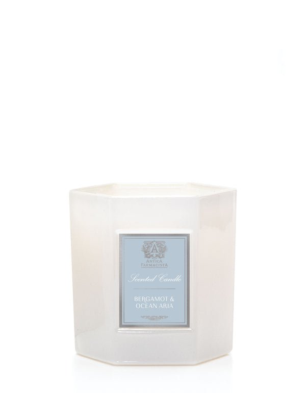 The Antica Farmacista - Bergamot & Ocean Aira 9oz Candle is a white, hexagonal soy-paraffin blend with a silver Bergamot & Ocean Aria label. It exudes oceanic notes and comes in a glossy, reflective holder.