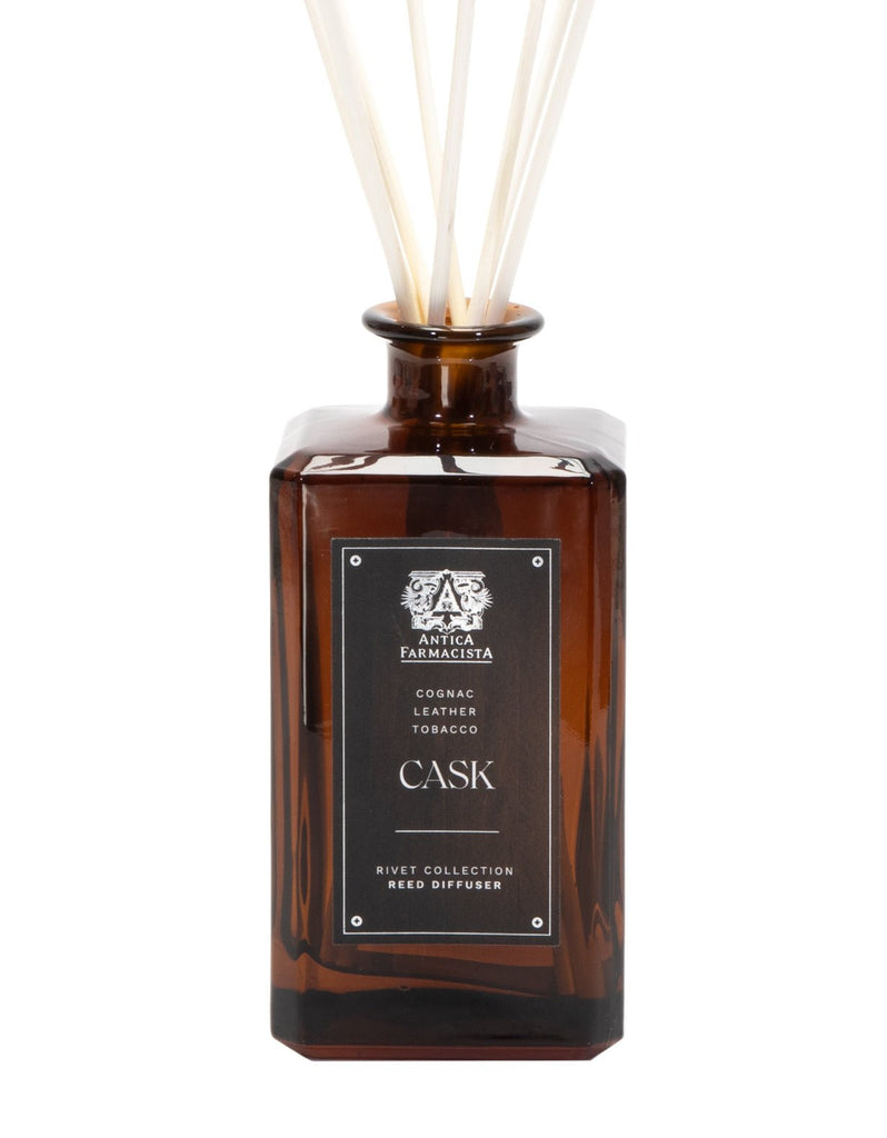 The Antica Farmacista - Cask 320ml Reed Diffuser exudes apothecary charm with an amber glass bottle and black Cask label, releasing rich cognac, leather, and tobacco notes through elegant white reeds for a sophisticated ambiance.