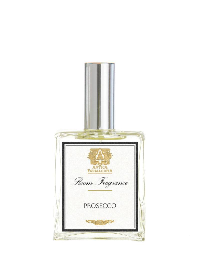 A rectangular glass bottle with a silver cap, labeled Antica Farmacista - Prosecco 100ml Room Spray, features a decorative emblem and elegant typography. It holds a clear liquid, suggesting a delightful room scent subtly infused with hints of Madagascar Vanilla.