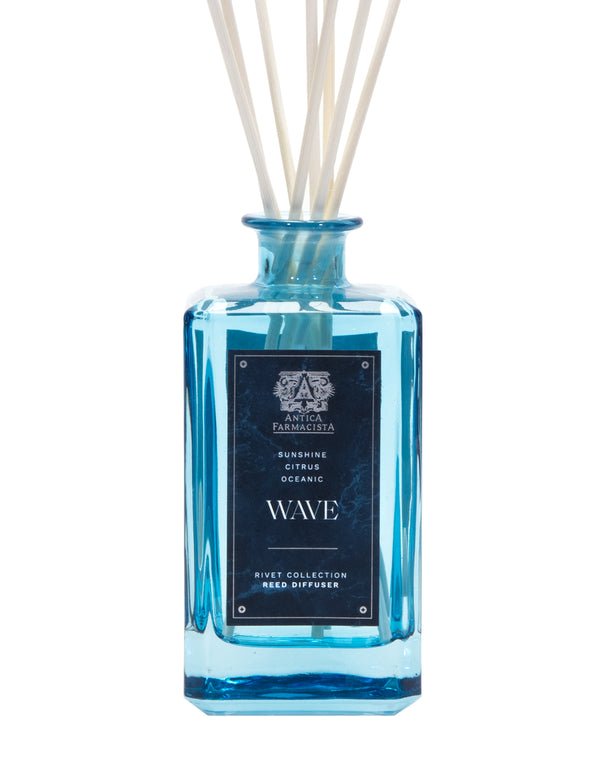 A blue glass bottle of Antica Farmacistas Wave 320ml Reed Diffuser from the Rivet Collection is labeled Sunshine Citrus Oceanic. Featuring white reeds, it captures marine notes with a hint of Meyer Lemon.