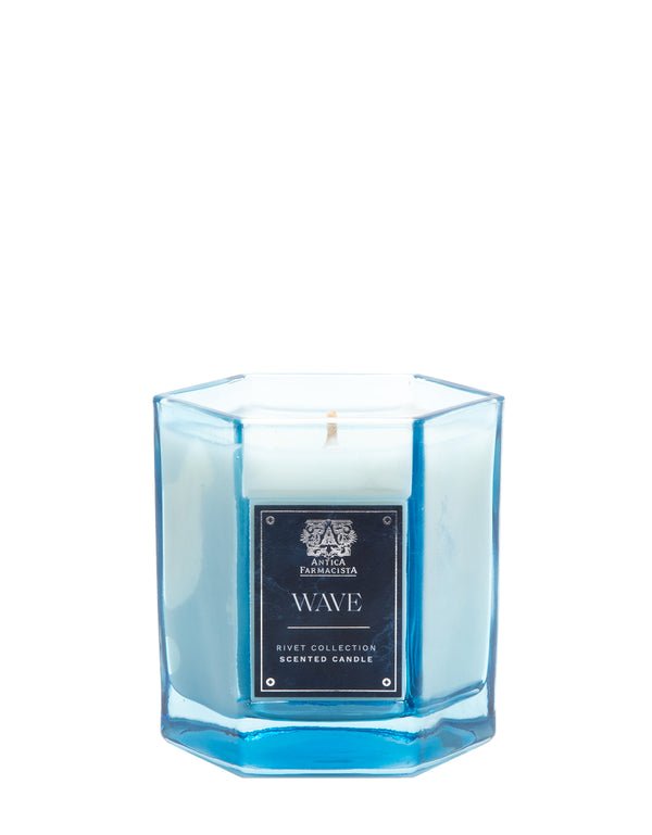 The Antica Farmacista - Wave 9oz Candle features a fresh Meyer Lemon scent in a blue hexagonal glass with a metal label. Crafted from soy-paraffin wax, it showcases Wave and an emblem, part of the Rivey Collection Scented Candle line.