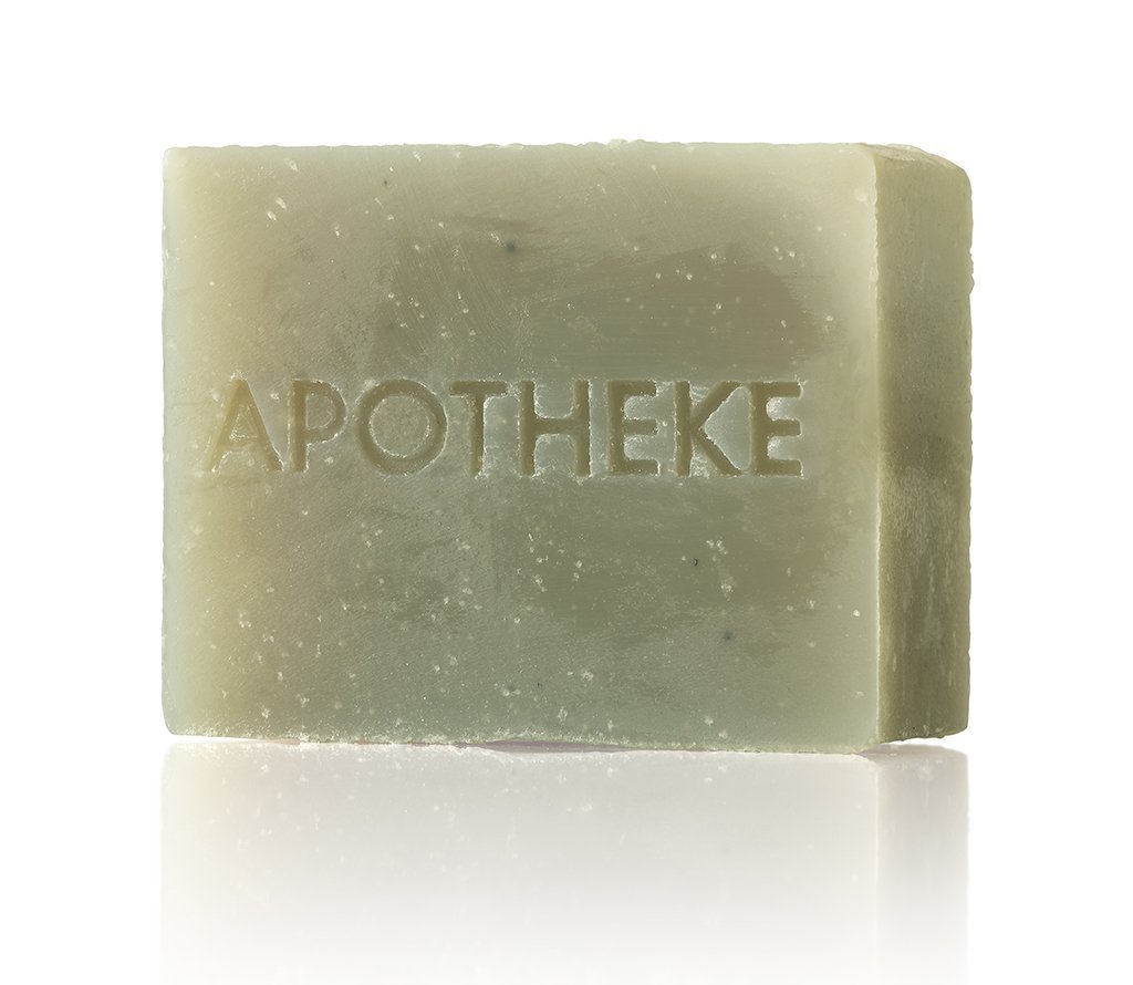 The Apotheke - Canvas Bar Soap showcases a muted green hue with APOTHEKE engraved, providing a plant-based moisturizing experience. Its smooth, slightly textured surface stands out against a white background.