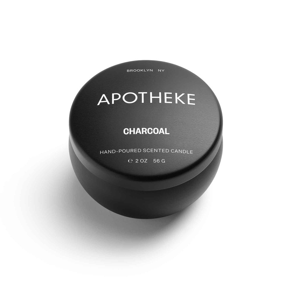 The Apotheke - Charcoal Mini Tin 2oz Candle is a black tin container from the Apotheke brand, labeled with CHARCOAL HAND-POURED SOY WAX BLEND MINI SCENTED CANDLE and weighing 2 oz (56 g). The lid reads BROOKLYN NY, against a white background.