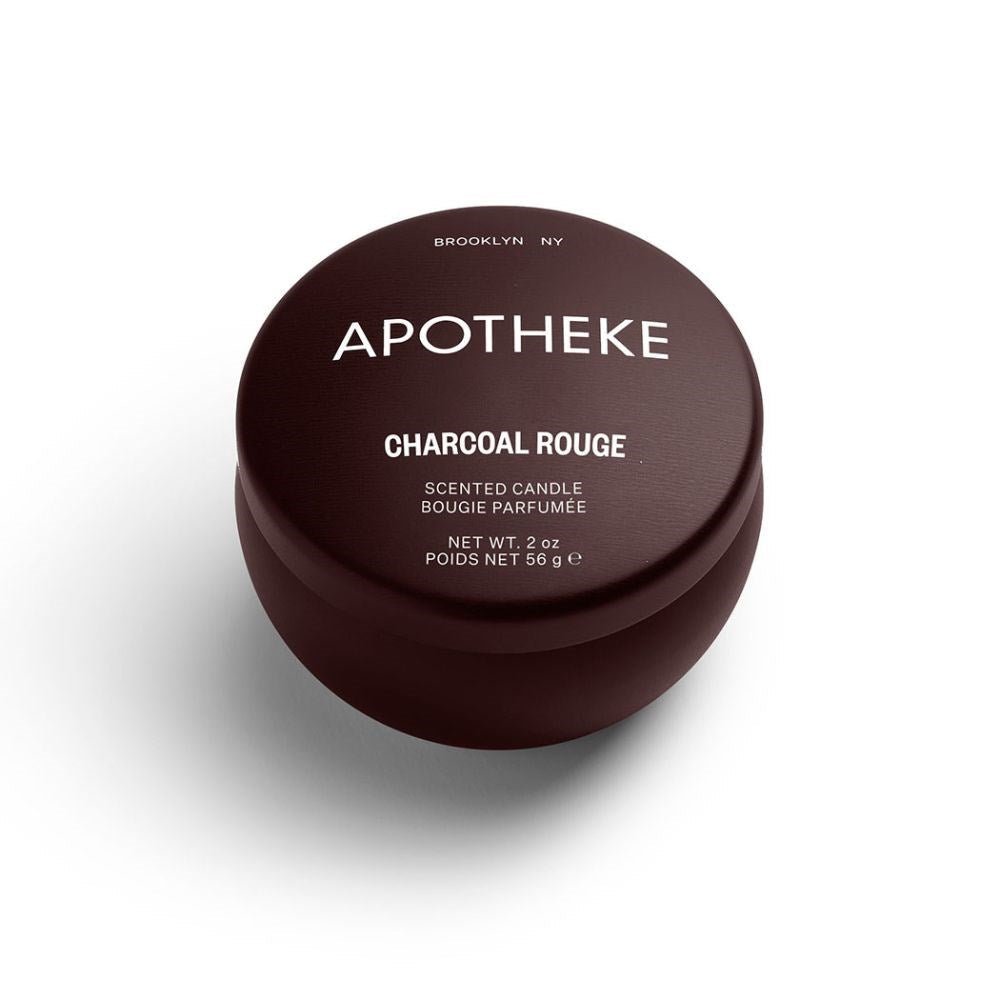 A round, dark brown mini candle tin with APOTHEKE and CHARCOAL ROUGE on the lid. This 2 oz Apotheke candle is crafted in Brooklyn, NY with a soy wax blend.