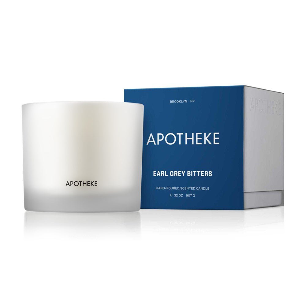 Apotheke - Earl Grey Bitters 3-Wick Candle features a white candle in a clear frosted glass with APOTHEKE label, accompanied by a matching blue box labeled EARL GREY BITTERS. Its hand-poured from a soy wax blend and made in Brooklyn, NY.