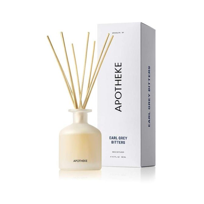 A frosted glass Apotheke - Earl Grey Bitters Reed Diffuser with wooden reeds and a white box, both labeled Apotheke, Earl Grey Bitters, features a minimalist design that enhances the elegance of any room with its refined fragrance oils.