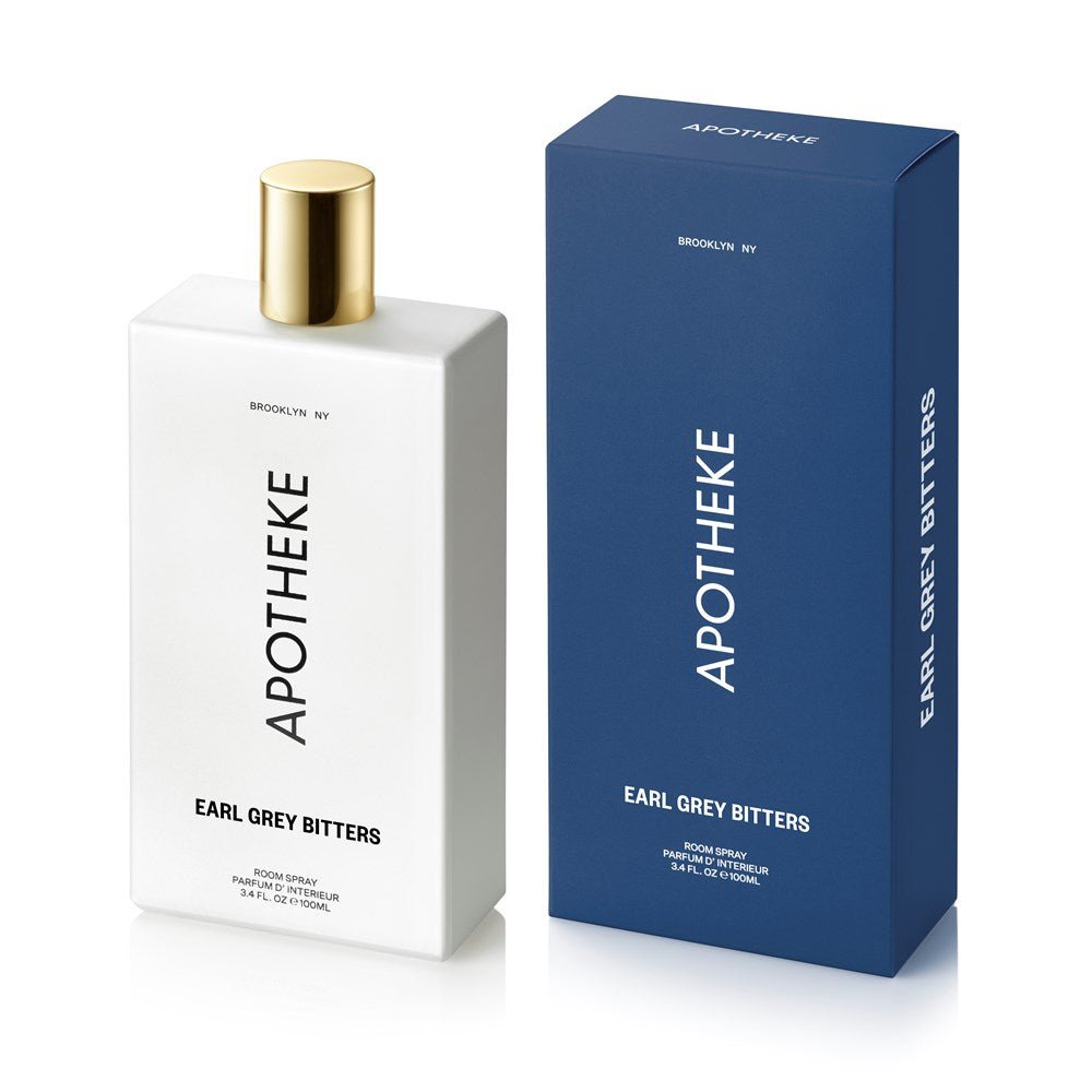 A white bottle of Apotheke - Earl Grey Room Spray with a gold cap is placed beside its blue box, both featuring the brand name Apotheke and scent Earl Grey prominently in capital letters.