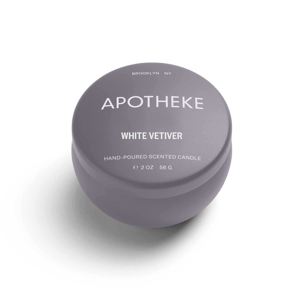 The Apotheke - White Vetiver Mini Tin 2oz Candle is a gray, round container with APOTHEKE label in bold white letters and WHITE VETIVER below. It includes HAND-POURED SOY WAX BLEND, weighs 56g, and mentions BROOKLYN NY at the top.