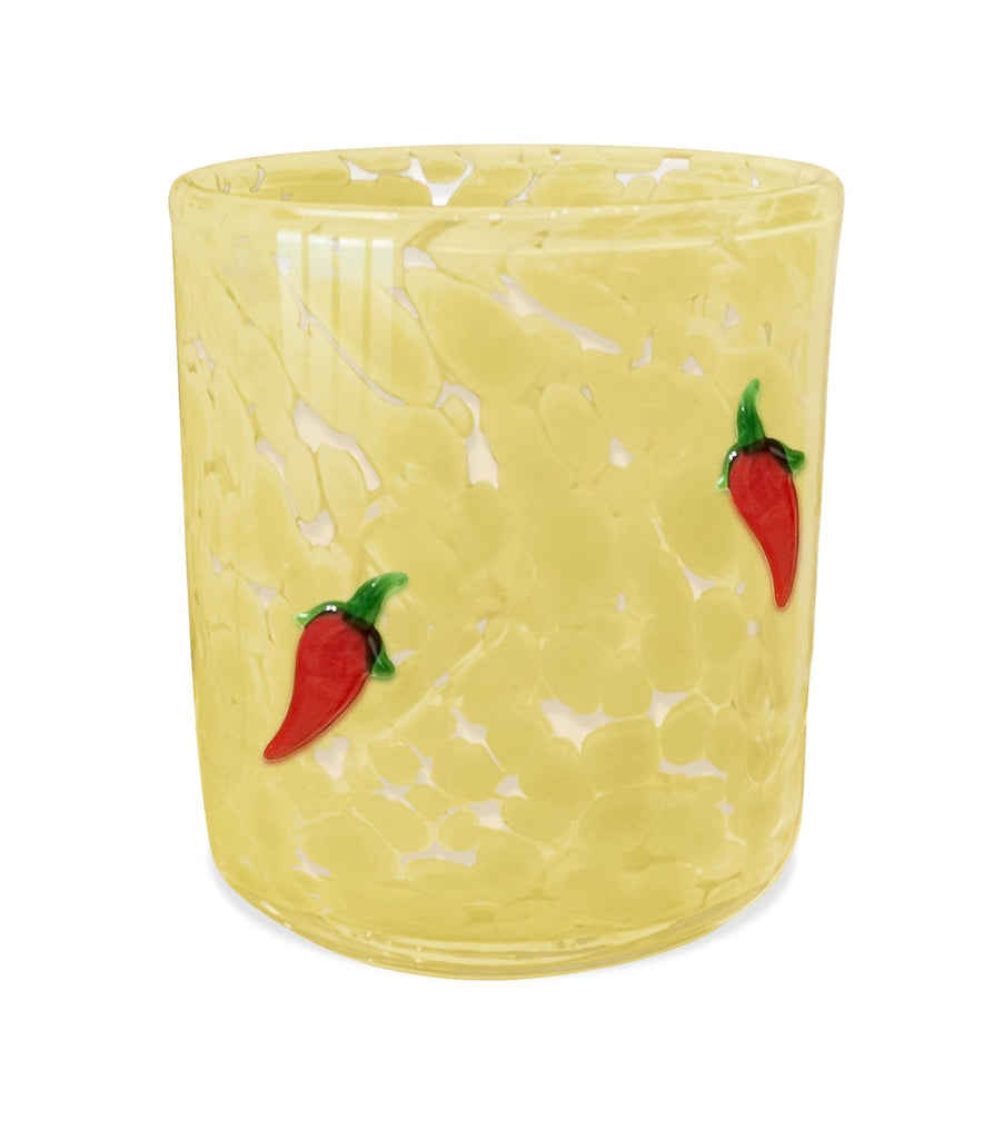 The Aqua De Soi - Golden Paloma 12 oz Confetti Candle, from Aqua De Soi, is housed in a yellow glass tumbler with a textured surface and two red chili pepper motifs, ideal for whimsical candlelight.