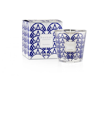 A 6.7oz decorative candle with an art deco design features a geometric blue and white pattern on its glass holder beside a matching box. Its labeled Moon Mountain from the Baobab Collection, making the My First Baobab Manhattan candle an ideal collectors item.