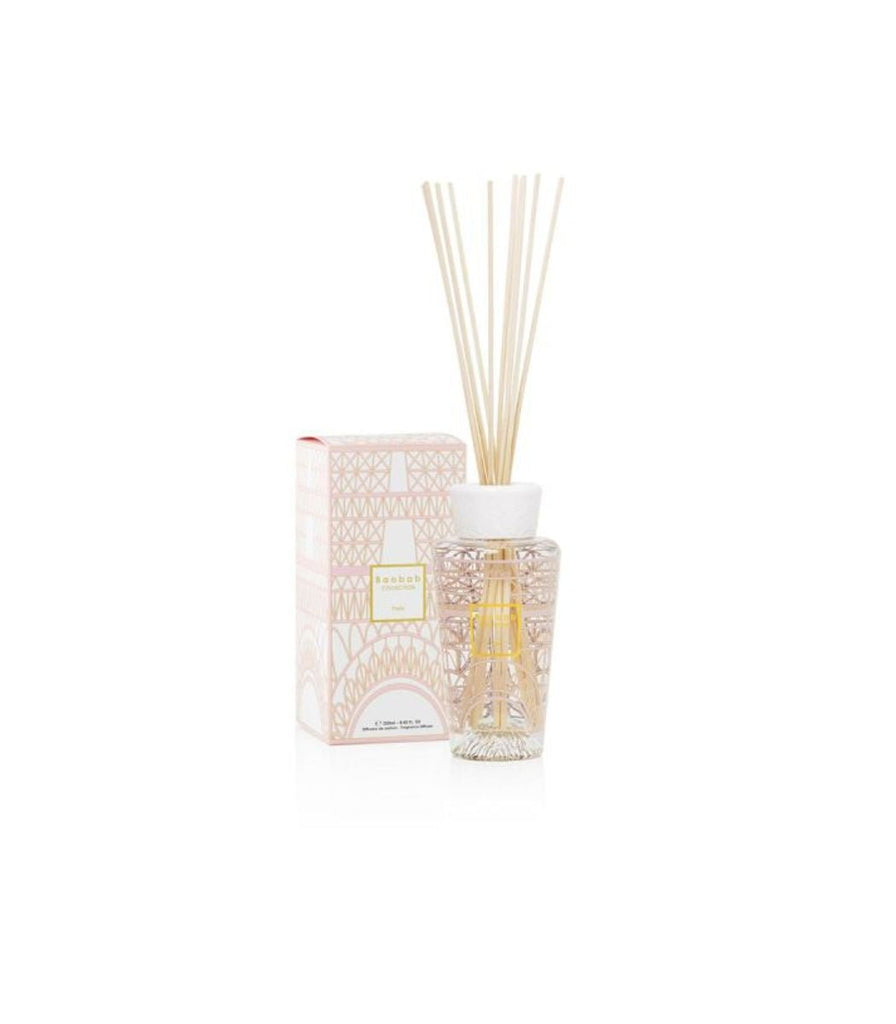 The Baobab - My First Baobab Paris 8.45oz Reed Diffuser features wooden sticks, a clear liquid bottle with a white cap, and an abstract pink and gold patterned box that adds an elegant touch of Paris home fragrance reminiscent of 24-carat design.