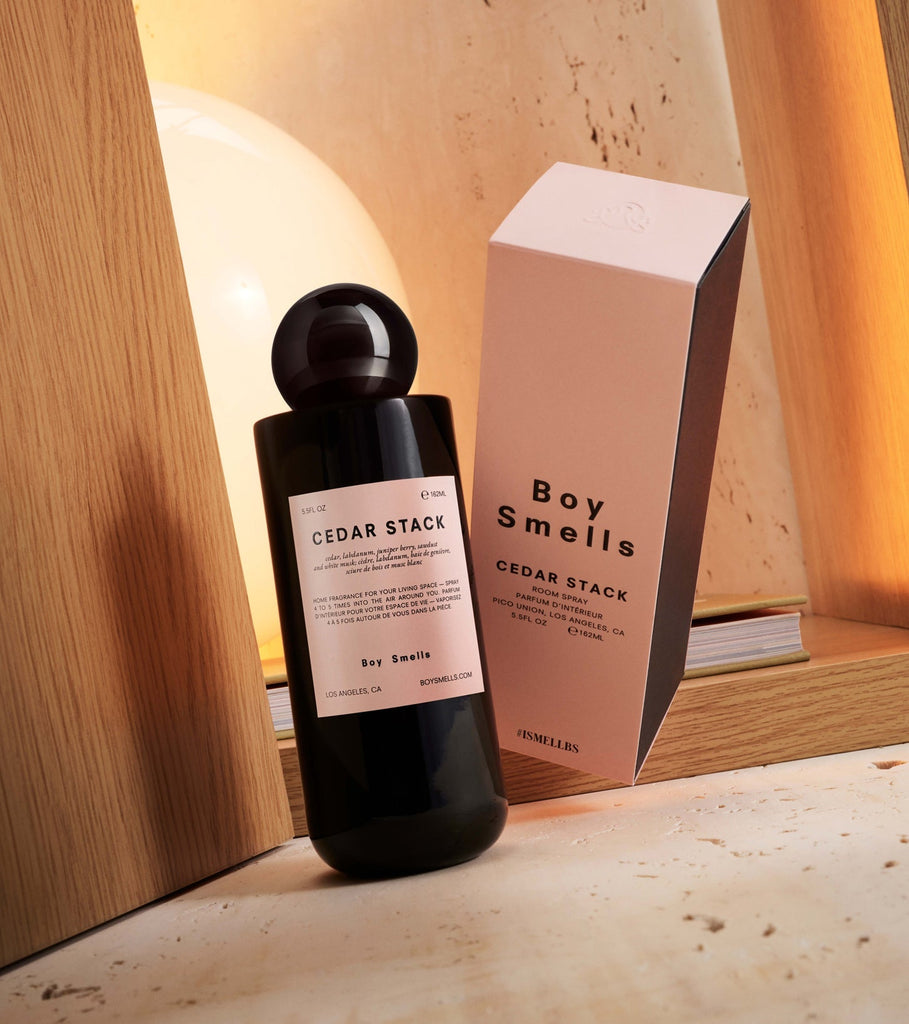 A minimalist black bottle labeled Boy Smells - Cedar Stack 5.5oz Room Spray sits by its Boy Smells box, exuding a calming wood scent. Elegantly placed on a wooden surface with warm lighting, it evokes the sophistication of an upscale room spray.