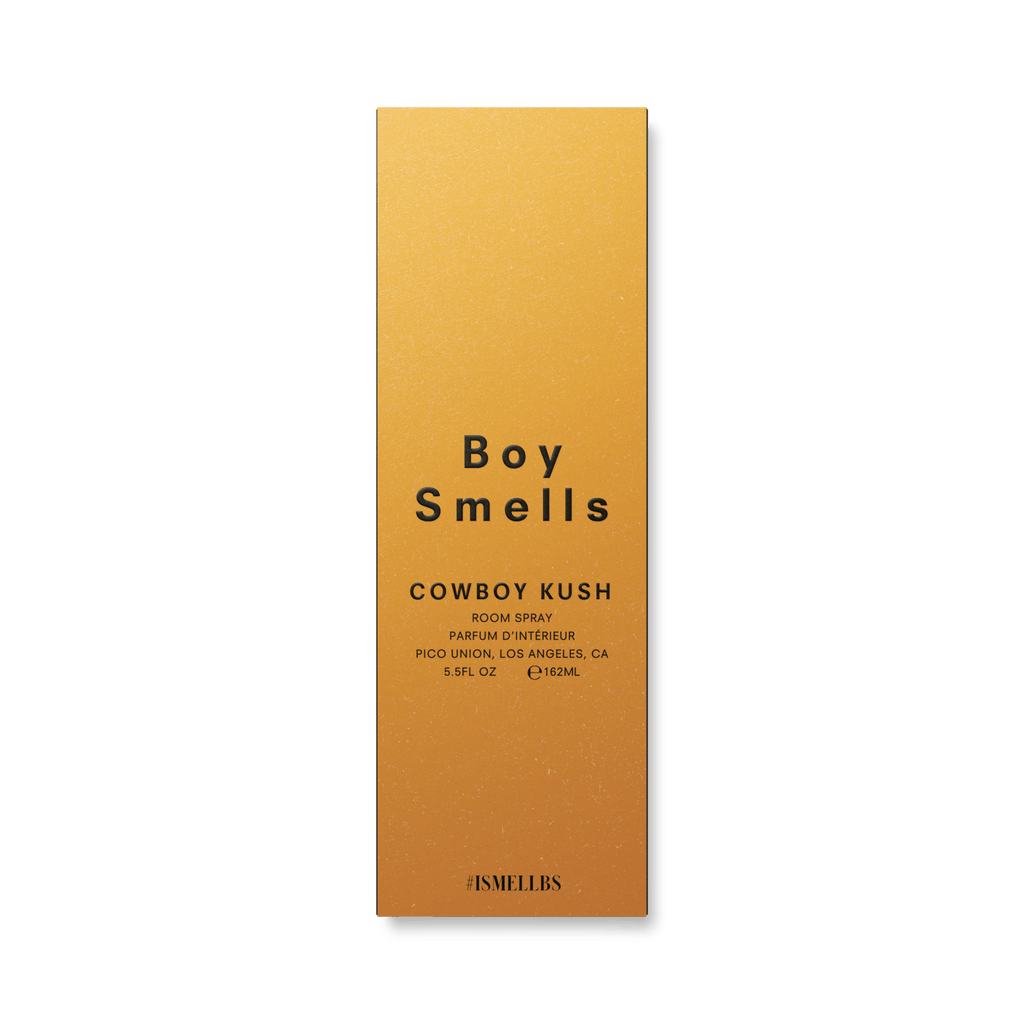 The golden box displaying Boy Smells unveils the earthy spice of Cowboy Kush 5.5oz Room Spray, crafted in Pico Union, Los Angeles, CA, with #ISMELLBS at the bottom.