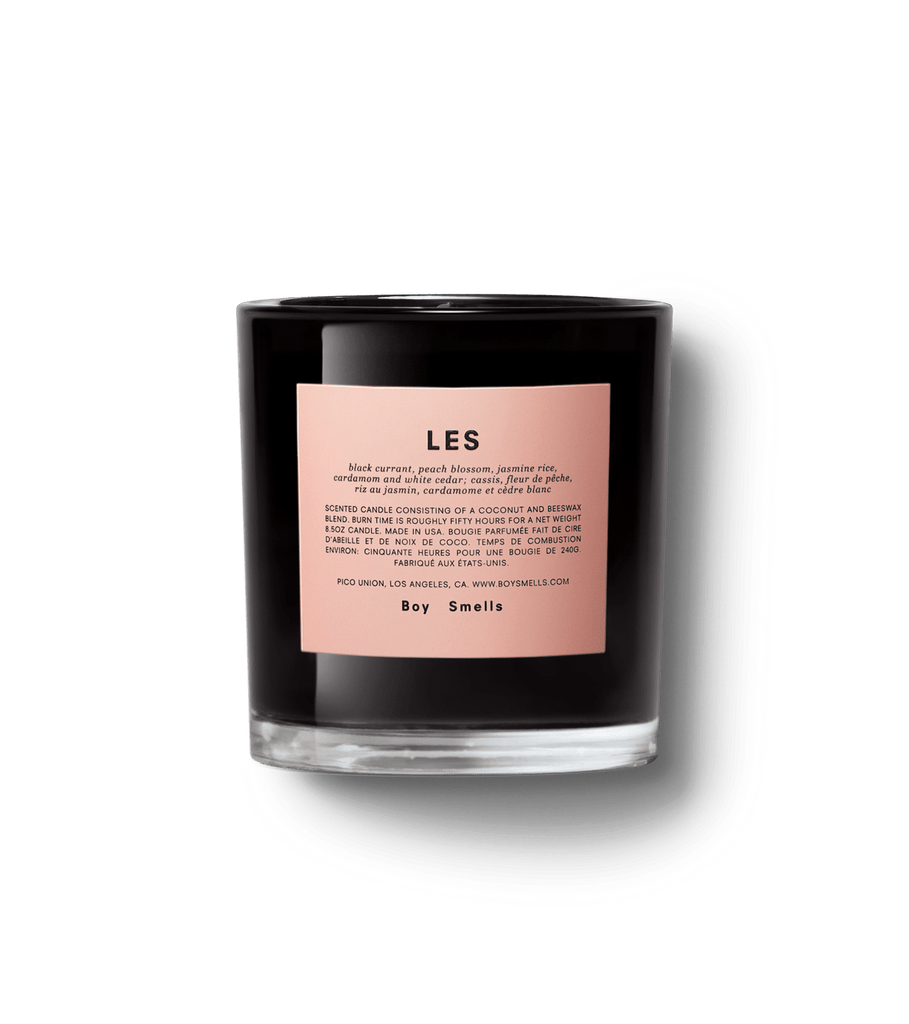 The Boy Smells - LES 8.5oz Candle in a black glass holder features a pink label detailing the fruity/floral scent and brand information, including Boy Smells at the bottom. This genderful candle, set against a white background, invites cross-cultural appreciation.