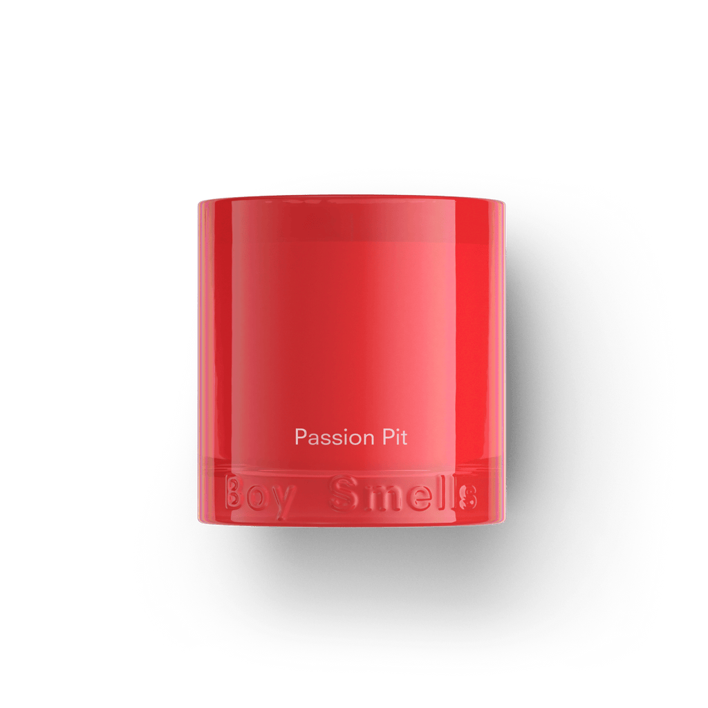 The Boy Smells - Passion Pit 8.5oz Candle features a bright red jar with the brand embossed at the base, set against a black backdrop, and delivers a fruity scent of passion fruit and orange.