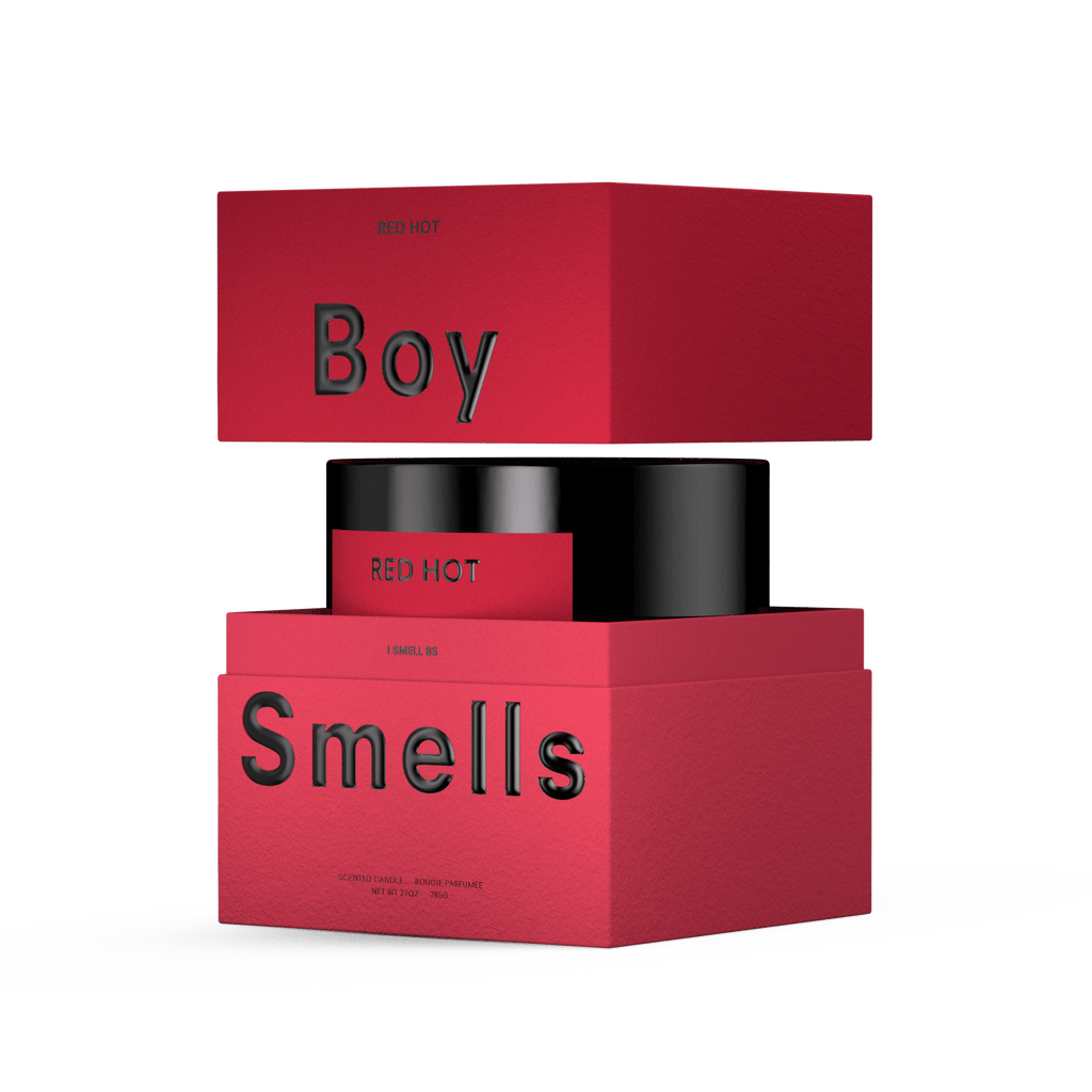A red box with black embossed "Boy Smells" and "Red Hot" text is shown partially open, revealing the Boy Smells - Red Hot 27oz Candle's black container inside, set against a plain white background.