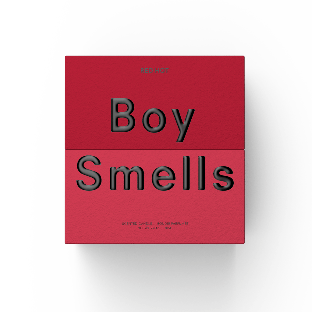 The Boy Smells - Red Hot 27oz Candle comes in a striking red and pink box with bold black "Boy Smells" and "Red Hot" text, packaging a vibrant, fruity spicy candle known for its bold scent and long-lasting burn.