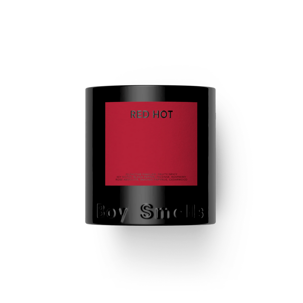 The Boy Smells - Red Hot 8.5oz Candle features a black jar with a red Red Hot label and embossed Boy Smells branding, offering a spicy scent. Shown against a plain white background.