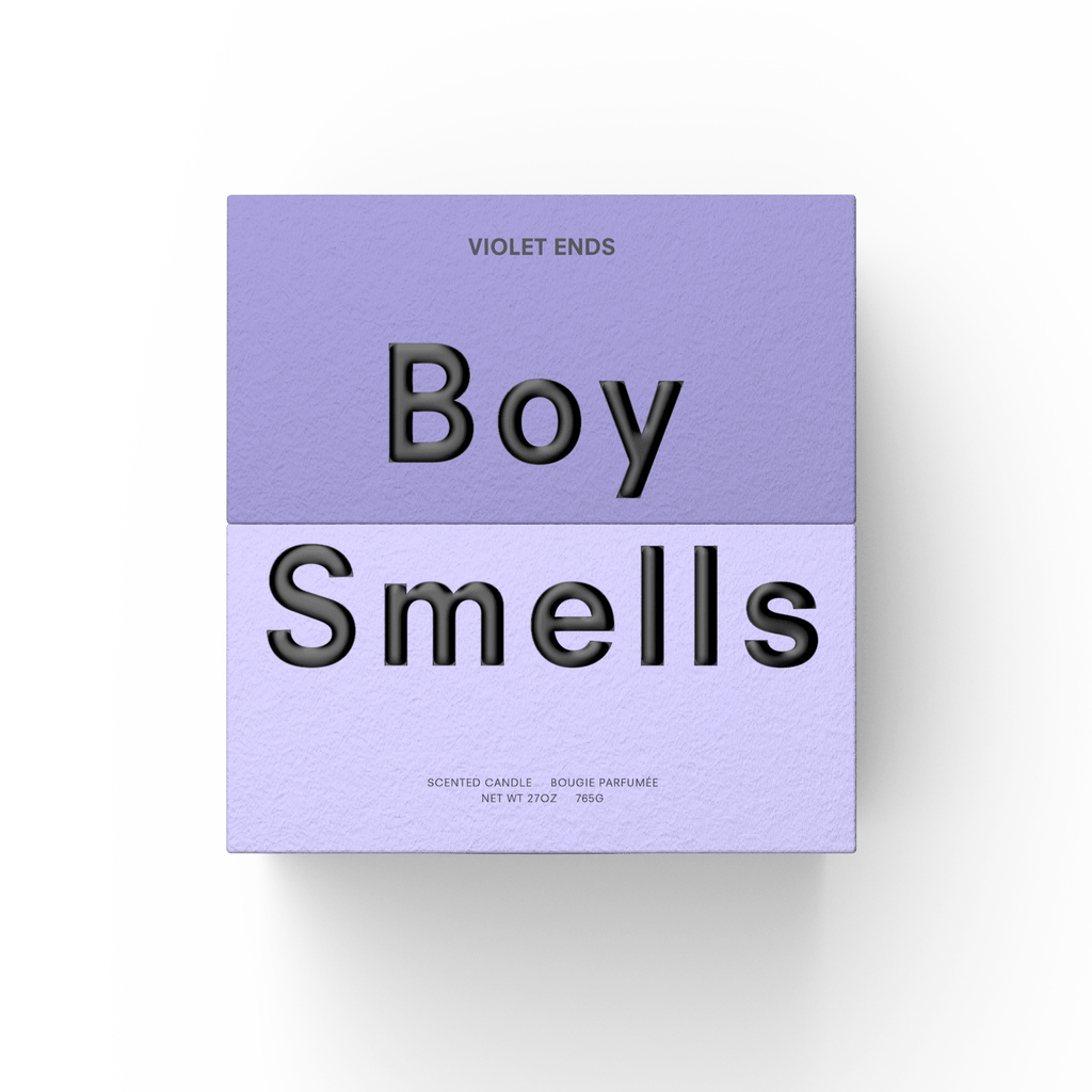 A square lavender box with "Violet Ends" at the top and bold "Boy Smells" text in the center houses the 27oz Boy Smells Violet Ends candle. Small text below describes it as an earthy floral scent with product details.