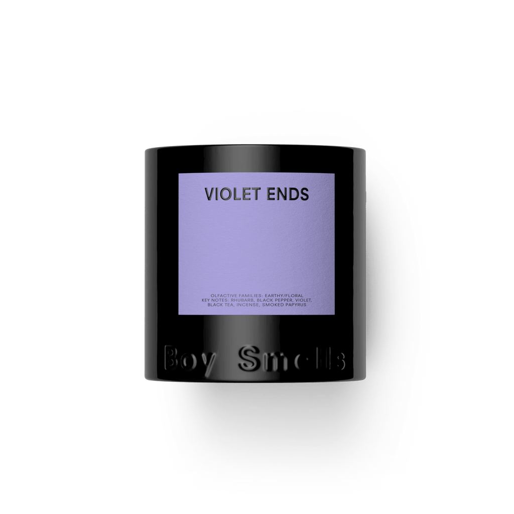 A black Boy Smells candle jar features a purple label with VIOLET ENDS in bold. The 8.5oz candle captures delicate floral and earthy scents, with the brand name embossed below, set against a white background.