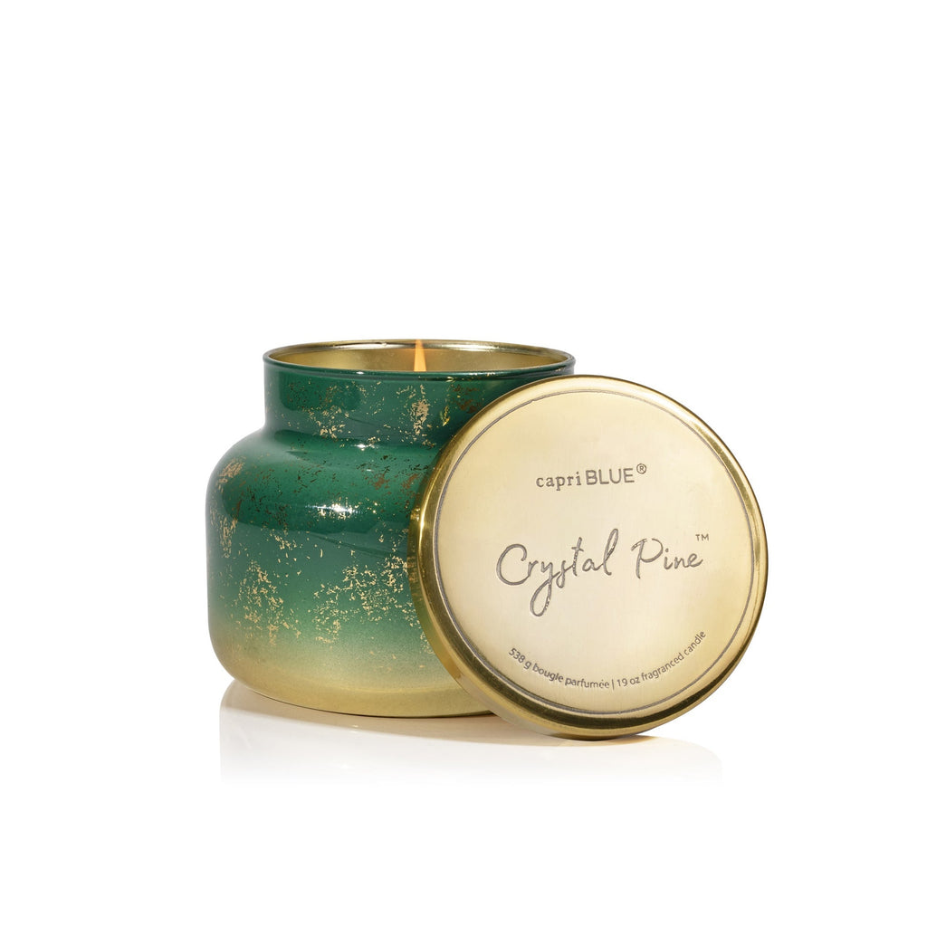 The Capri BLUE - Crystal Pine Glimmer Signature Candle, 19oz, features a green and gold vessel with gold speckles and a gold lid beside pine-scented wax—perfect for adding cozy winter ambience.