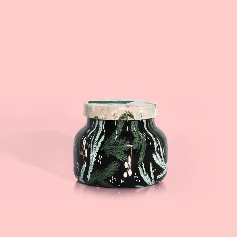 The Capri BLUE Crystal Pine Holiday Pattern Play Petite Jar Candle features a green, nature-themed design with leaves and flowers on a matching lid, all against a pink background.