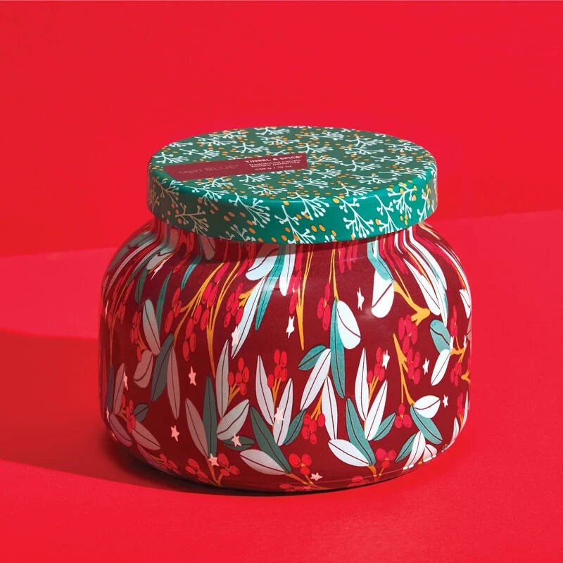 The Capri BLUE Tinsel & Spice Holiday Pattern Play Signature Jar 19 oz Candle features a festive design with a floral pattern on vibrant red, green leaves, and white flowers, topped with a tinsel and spice-themed lid for added charm and elegance.