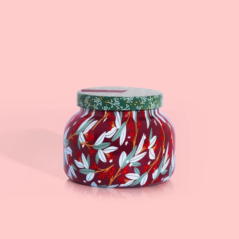 The Capri BLUE - Tinsel & Spice Holiday Pattern Play Signature Jar 19 oz Candle features a festive design with a green lid, white and blue leaves, tiny flowers on a vibrant red background, and pink accents for warmth and charm.