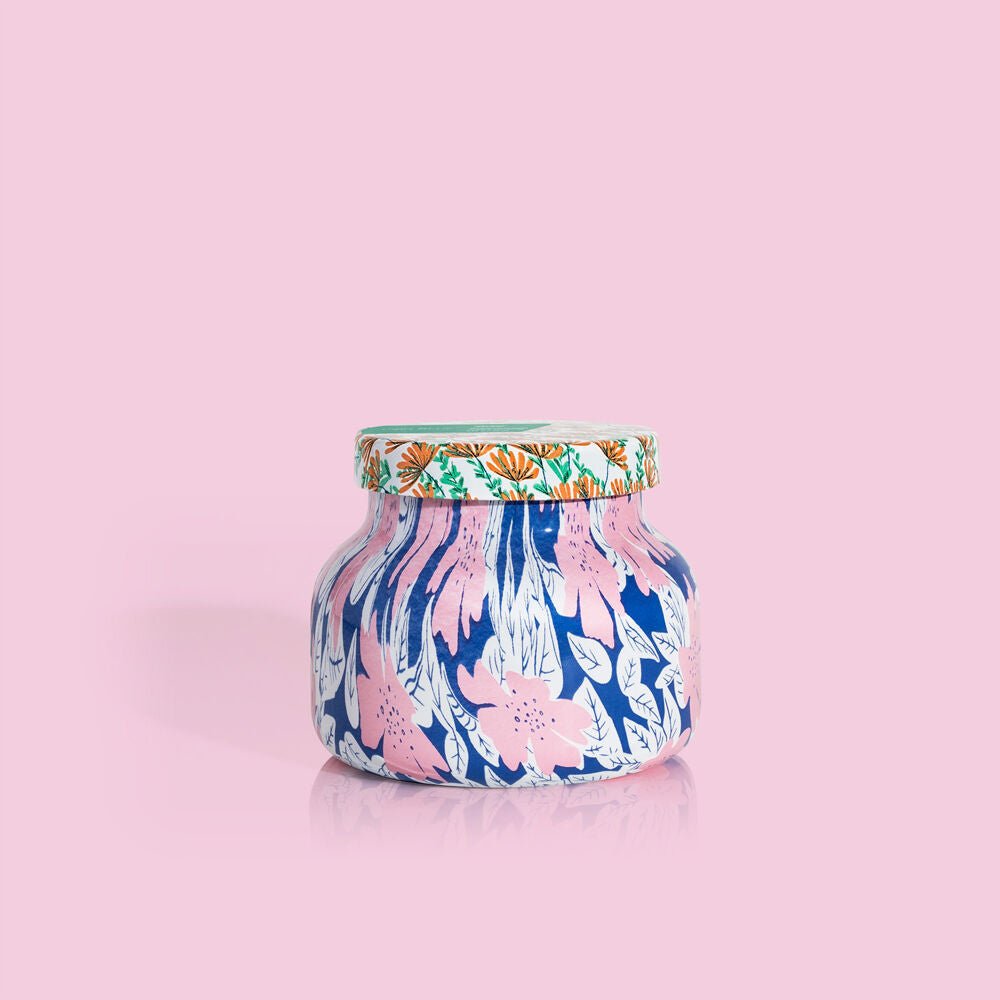 The Capri BLUE - Volcano Pattern Play Petite Jar, 8 oz features a pink and white floral design on blue with a green lid and orange accents, set against light pink. Enjoy the refreshing sugared citrus scent of the signature Volcano fragrance.