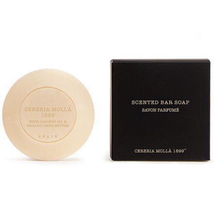 The Cereria Molla Basil & Mandarin 3.5oz scented bar soap, enriched with nourishing coconut oil and organic shea butter, is displayed beside its sleek black box, with elegant packaging showcasing the brand and product details.