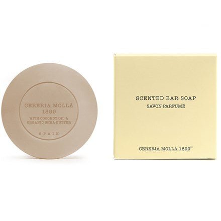 A round bar of Cereria Mollas Bergamotto Di Calabria 3.5oz scented soap, enriched with organic shea butter and embossed with text, is next to its cream-colored box labeled Scented Bar Soap and Cereria Mollá 1899, featuring additional text in French and Spanish.