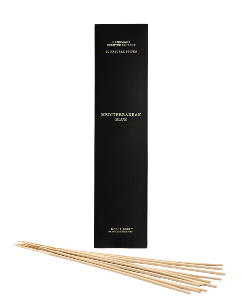 The tall, elegant Cereria Molla - Mediterranean Blue Incense 20pk box stands upright, with handmade sticks beside it. These exude a captivating fragrance reminiscent of serene Mediterranean shores.