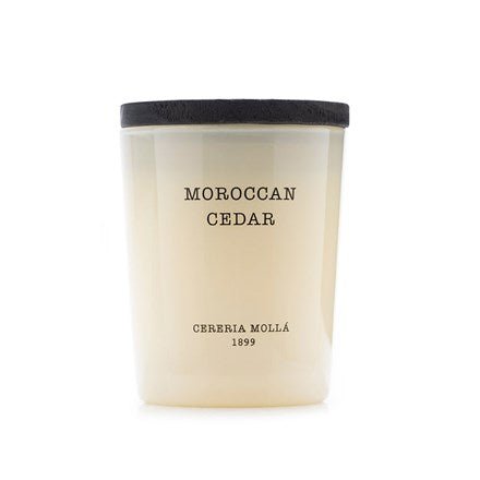 The Cereria Molla - Moroccan Cedar 2.6oz Candle is crafted with premium soy wax, housed in a light cream container with a black lid. Moroccan Cedar and Cereria Mollá 1899 elegantly adorn it, exuding timeless sophistication.