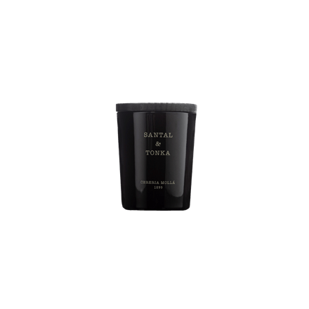 The Cereria Molla - Santal & Tonka 2.6oz candle in a black glass holder features Santal & Tonka and Cereria Mollá 1899 elegantly in white. Its exquisite soy wax blend delights with subtle cedar oil undertones enhancing the rich aroma.