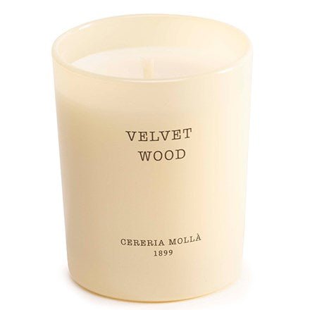 Cream-colored scented candle in a glass holder, emblazoned with Velvet Wood and the smaller inscription Cereria Molla 1899, capturing the essence of aromatic spices.