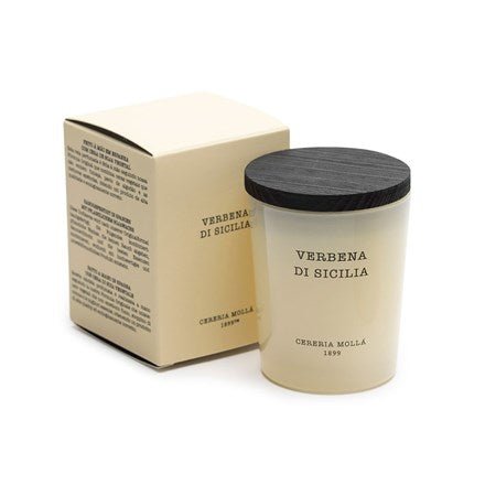 A cream-colored Cereria Molla - Verbena De Sicilia 2.6oz soy wax candle with a dark wooden lid is displayed next to its beige box featuring black text. Both candle and box elegantly showcase the brand, Cereria Molla.