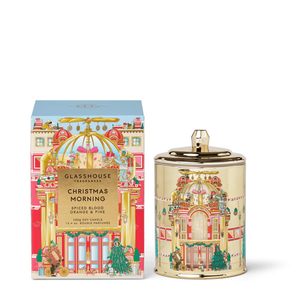 The Glasshouse Fragrances - Christmas Morning 13.4oz Candle comes in a festive illustrated box, capturing holiday spirit with its spiced blood orange & pine scent.
