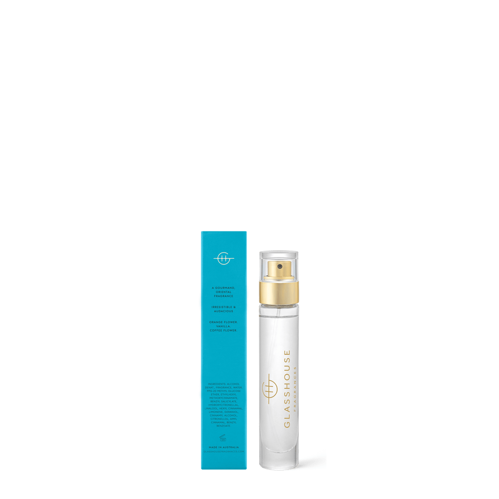 A Glasshouse Fragrances Eau de Parfum 14ml - Melbourne Muse bottle, displaying a white and gold design, is placed next to a blue rectangular box with text. The setup exudes vanilla notes on a plain white background.