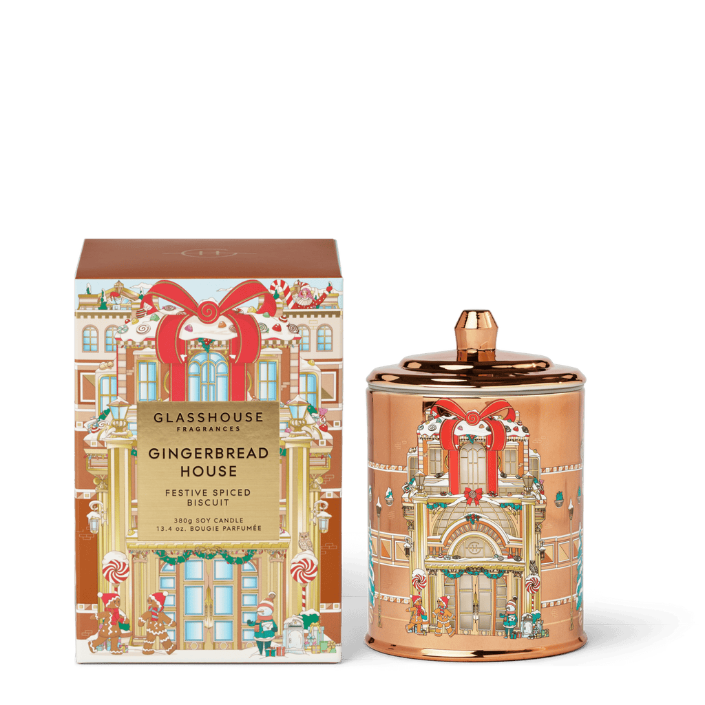 The Glasshouse Fragrances - Gingerbread House 13.4oz Candle comes in a festive copper jar and illustrated box, both adorned with gingerbread house designs and holiday motifs—perfect for decorative, scented holiday ambiance.