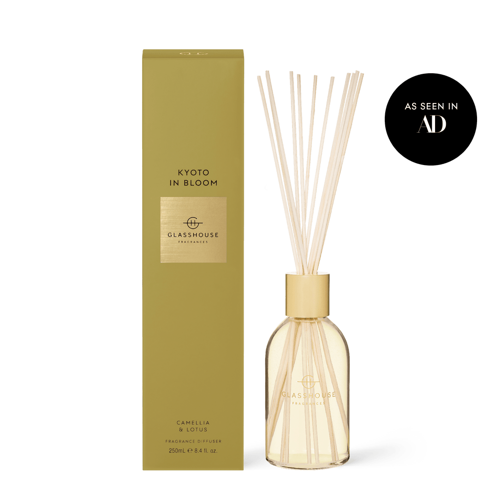 The Glasshouse Fragrances - Kyoto in Bloom Diffuser, featured in AD, offers a 250mL serene aromatic blend of Camellia and Lotus. Its elegant design includes a clear bottle with reeds and a gold box.