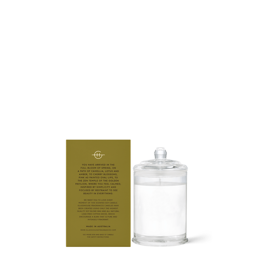 A Kyoto in Bloom 2.1oz candle by Glasshouse Fragrances, known for its triple scent with Camellia and Lotus, sits beside a gold card. Labeled The Pool, this Australian-made candle offers an exquisite aroma with natural cotton wicks in collaboration with 1969 and Lux.