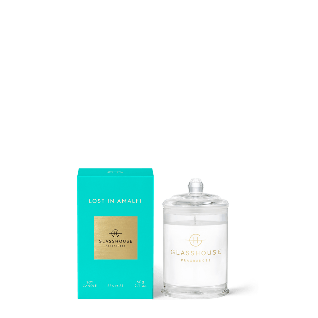 The 2.1oz Lost in Amalfi mini candle by Glasshouse Fragrances comes in a teal box with a clear holder featuring the brands logo. It offers the Sea Mist scent and is crafted from a non-toxic soy blend wax for a safe, aromatic experience.