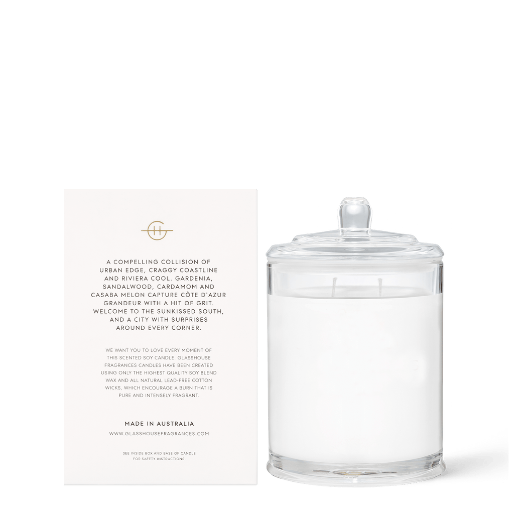 The Glasshouse Fragrances - Marseille Memoir 13.4oz Candle, with a gardenia and neroli scent, features white wax, two wicks, and a lid. Made in Australia by Glasshouse Fragrances, it sits beside an upright white card detailing its triple-scented fragrance.