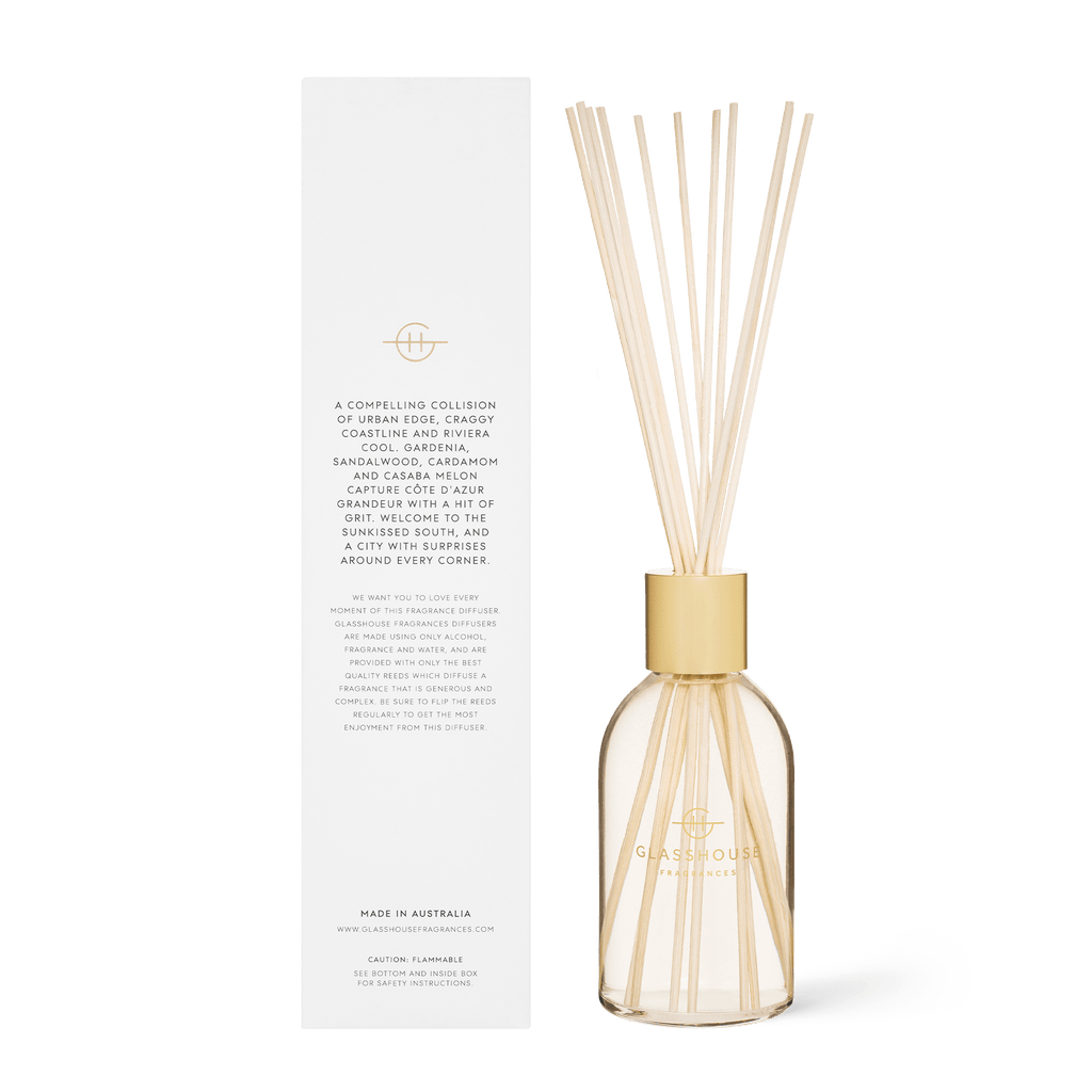 The Gardenia-scented Glasshouse Fragrances - Marseille Memoir Diffuser is a flameless glass aromatherapy diffuser with reeds, featuring a gold lid and elegant brand logo. It comes beside its box, which displays details in gold and black text. Enjoy this serene diffuser today.