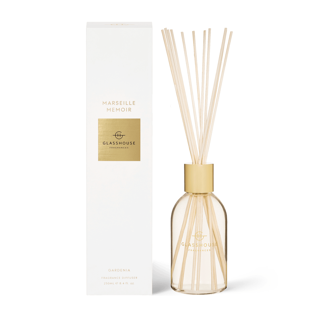 The Glasshouse Fragrances - Marseille Memoir Diffuser, featuring a glass container and wooden reeds, is elegantly paired with a white and gold box. This stylish flameless diffuser releases an enchanting Gardenia aroma throughout the room.