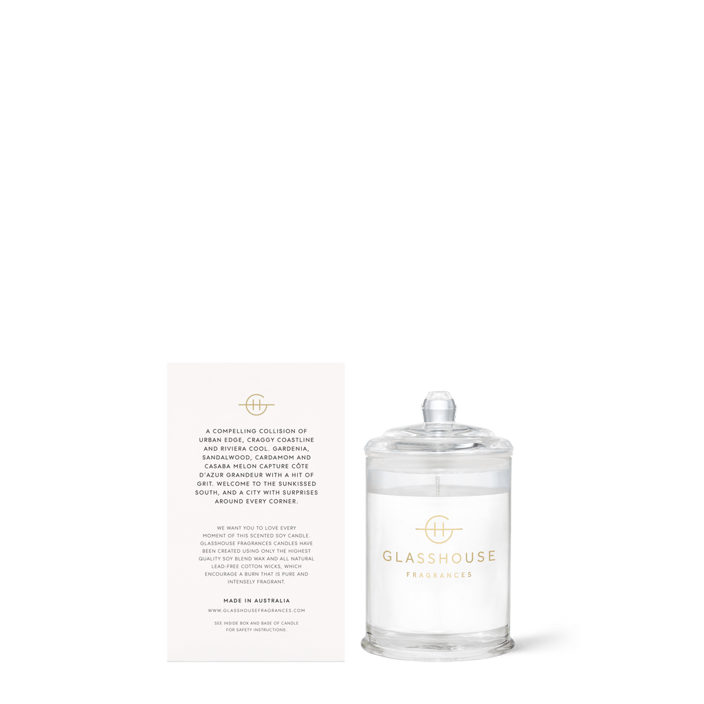 The Glasshouse Fragrances - Marseille Memoir Mini 2.1oz Candle boasts a minimalist design with a clear lid and white product card. This triple-scented soy candle offers the enchanting Gardenia fragrance for an elegant experience.